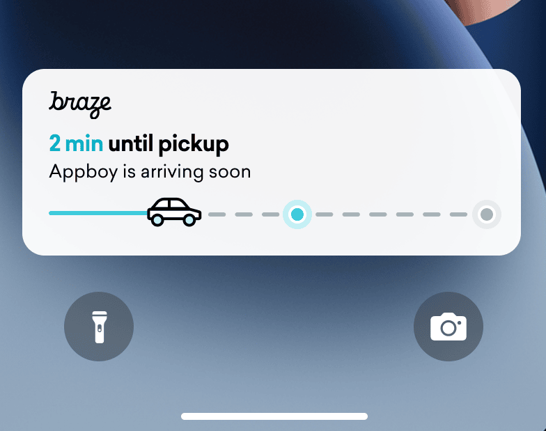 iPhone ロック画面の配信トラッカーのライブアクティビティ。車のついたステータス棒がほぼ半分に満ちている。「ピックアップまで2分」というテキストが表示されています